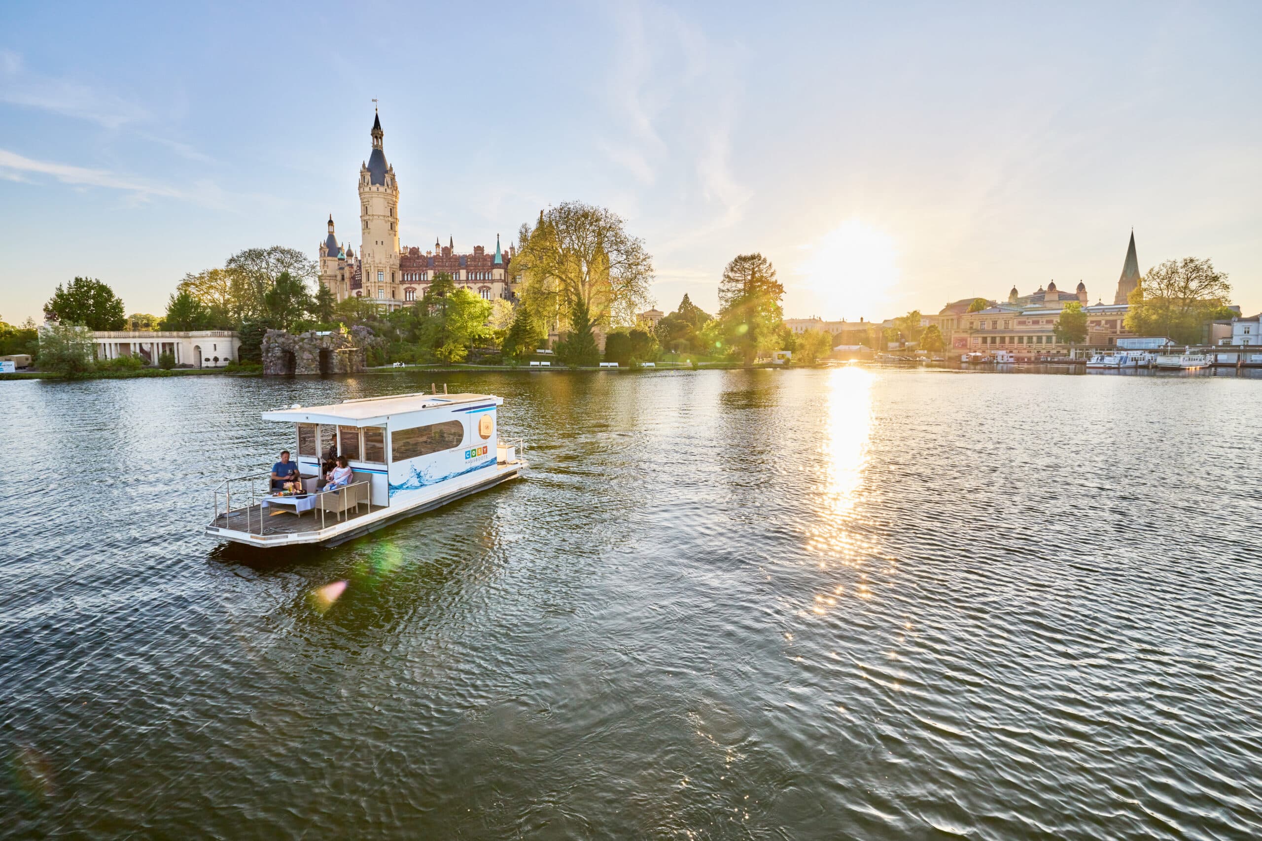 COSY Hausboote Schwerin, Stadtmarketing Schwerin, Fotograf Oliver Borchert, Hausboot auf dem Wasser fahrend, Schweriner See, Schweriner Schloss