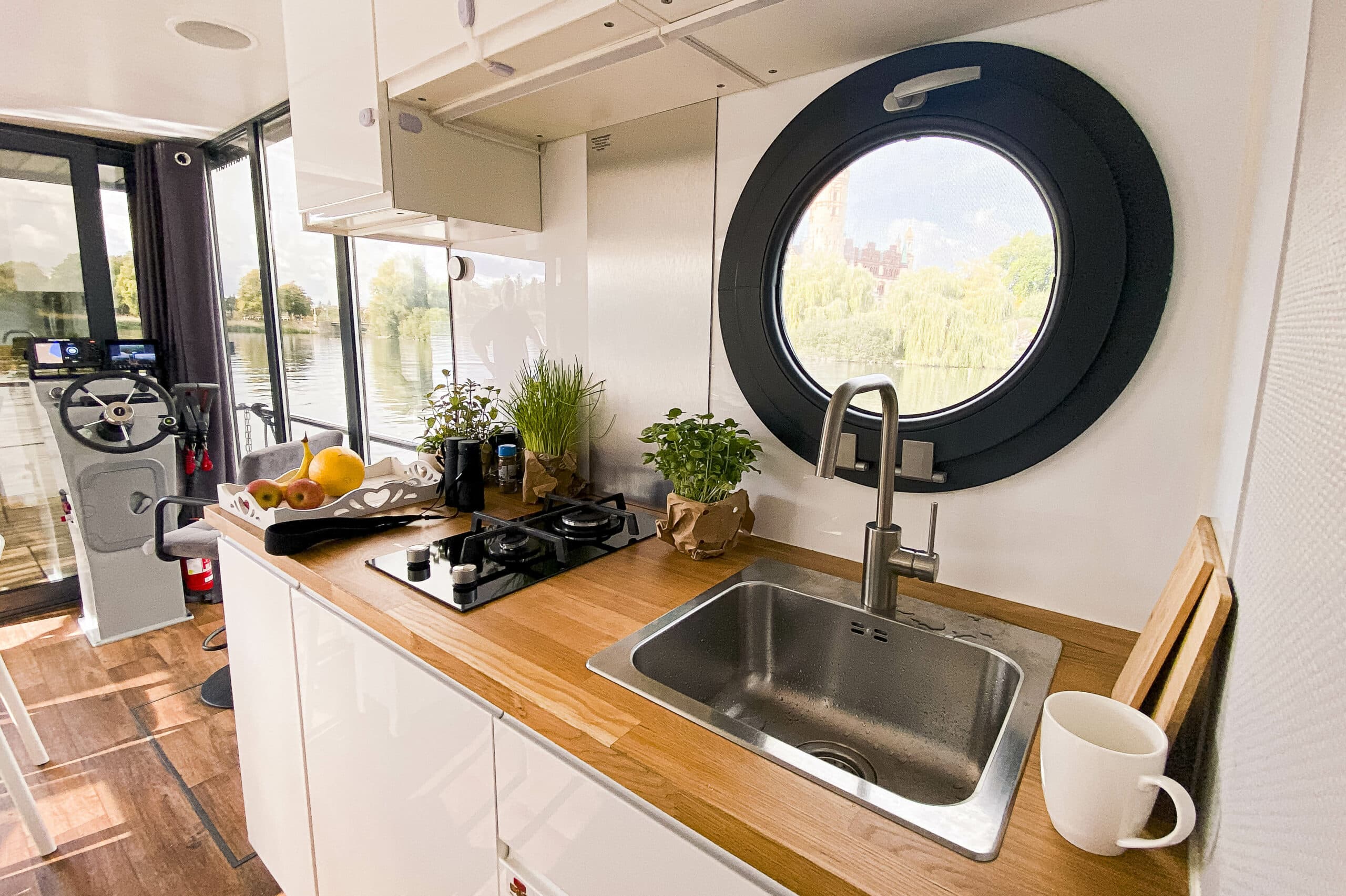 Hannah, COSY Hausboote, Wohnraum Küche mit Fenster und Steuerrad